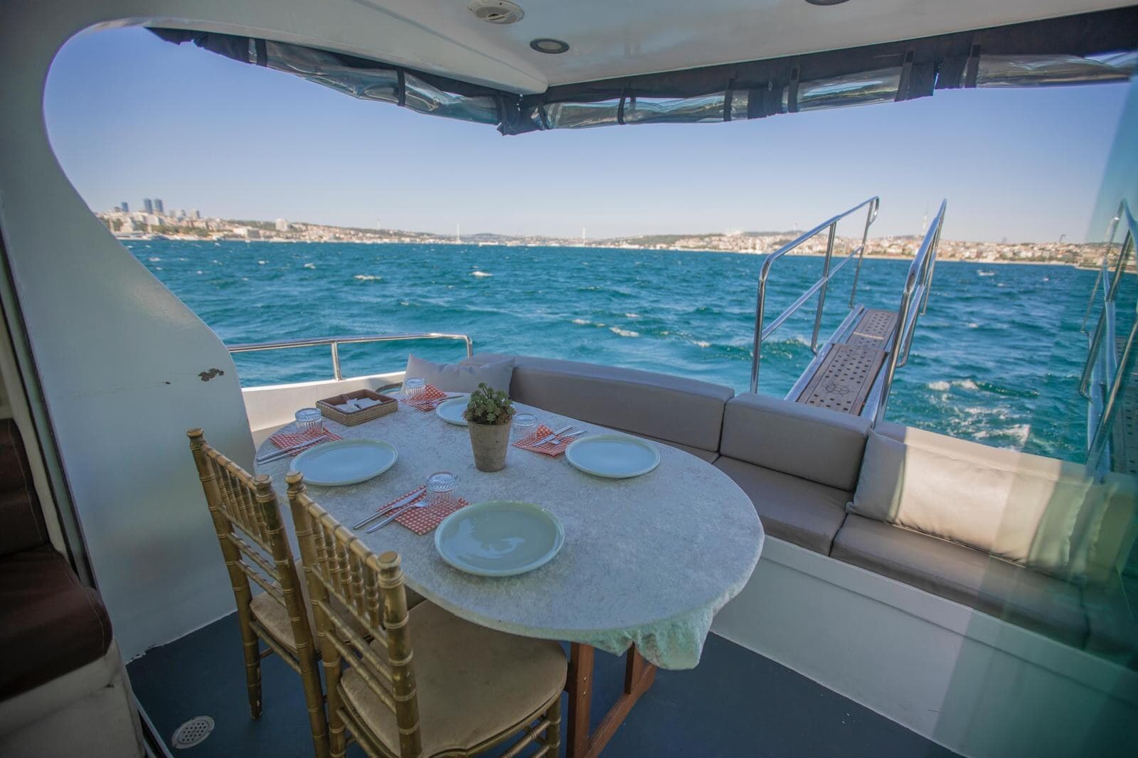 Aft deck table laid for dinner with the Bosphorus shoreline behind