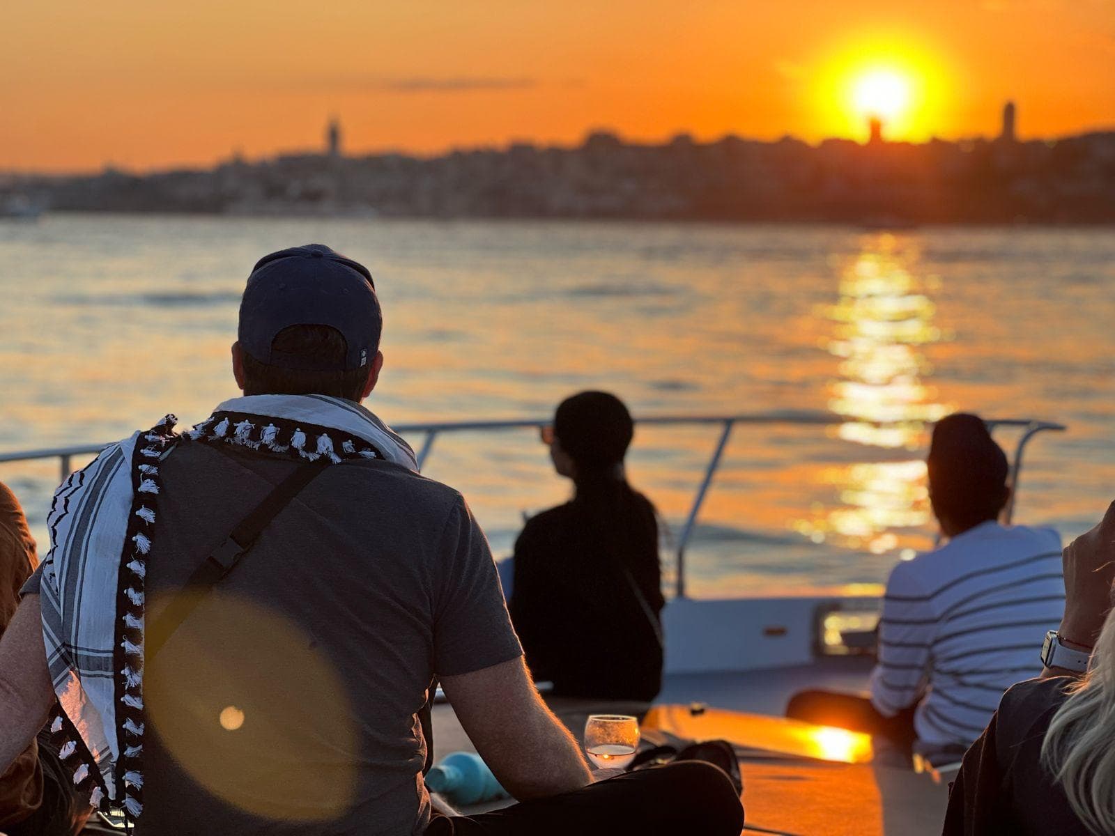 Guests on deck as the sun drops over the Bosphorus at golden hour, Istanbul